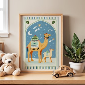 May include: A framed art print featuring a camel and its calf against a blue night sky with stars and a crescent moon. The camel is adorned with decorative saddle blankets. The artwork is in a wooden frame, and the overall theme is a desert scene.