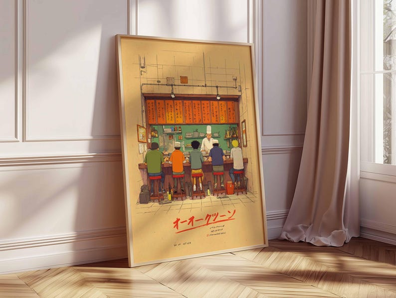 May include: Framed art print depicting a Japanese ramen shop scene. The illustration shows a chef behind a counter serving customers seated at a bar. The artwork features warm colors and Japanese text.