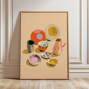 Pode incluir: Uma impressão de arte emoldurada com uma ilustração de natureza morta de vários recipientes de cerâmica, incluindo um jarro às riscas, taças e chávenas em tons de laranja, amarelo, rosa e verde sobre um fundo bege claro com sombras.