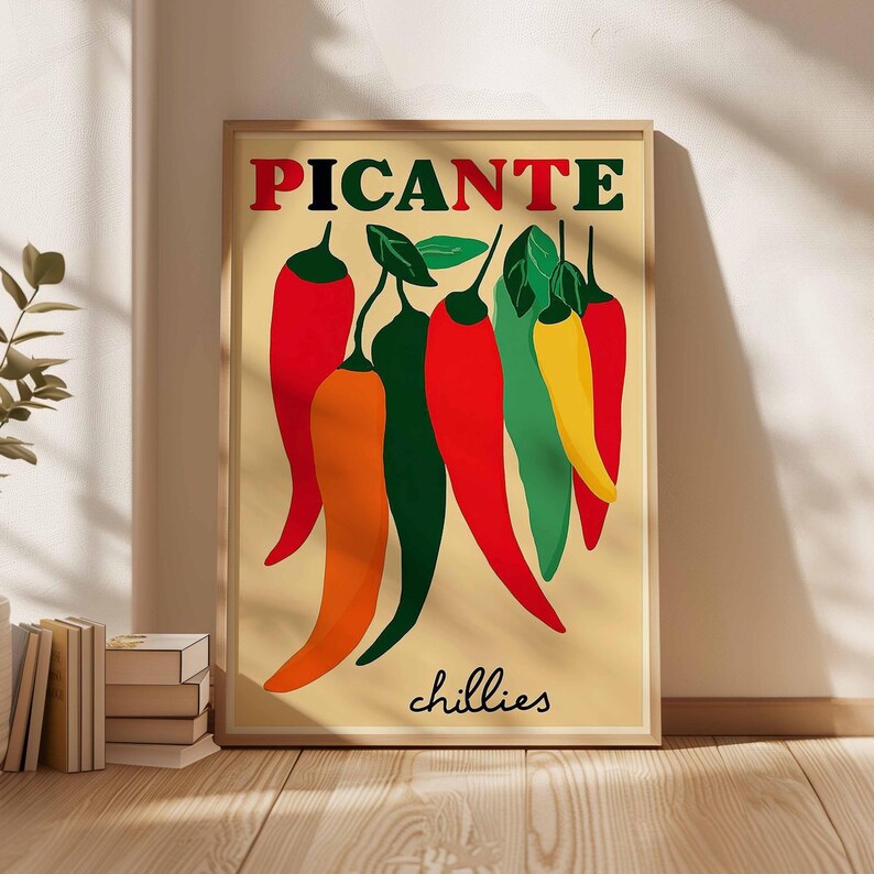 May include: A framed art print featuring a stylized illustration of chili peppers. The word "PICANTE" is at the top in red letters, with the word "chillies" at the bottom. The peppers are in shades of red, orange, green, and yellow.