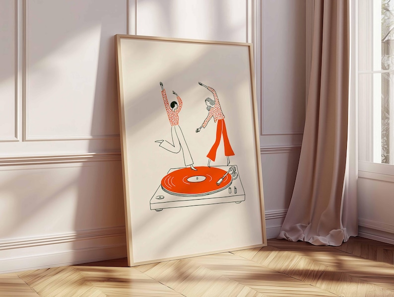 Puede incluir: Una impresi&oacute;n art&iacute;stica enmarcada con una ilustraci&oacute;n caprichosa de dos figuras bailando sobre un tocadiscos. Las figuras est&aacute;n representadas en rojo y blanco, con el tocadiscos en naranja y gris. La obra de arte tiene un estilo minimalista y un fondo crema.