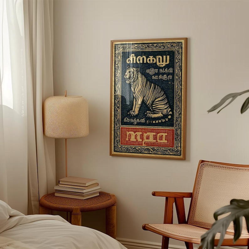 May include: A framed vintage-style poster featuring a tiger illustration. The poster has a dark blue background with gold accents and text in a foreign language. The bottom section of the poster is red with more text. The frame is a light brown color.