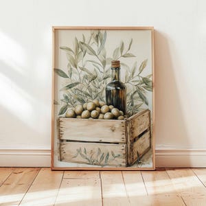 May include: Watercolor print of olives, olive oil bottle, and olive branches in a wooden crate. The artwork has a rustic, vintage aesthetic, with soft colors and a focus on natural elements. The print is framed.