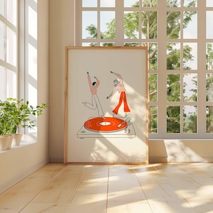 Puede incluir: Una impresi&oacute;n art&iacute;stica enmarcada con una ilustraci&oacute;n minimalista de dos figuras bailando sobre un tocadiscos. El tocadiscos tiene un disco naranja. Las figuras llevan camisas y pantalones con estampados rojos y blancos. La obra de arte se exhibe en una habitaci&oacute;n con luz natural.