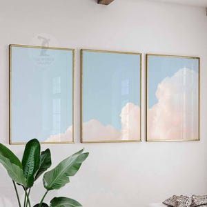 Puede incluir: Tres impresiones artísticas enmarcadas con un diseño de cielo y nubes. Las impresiones tienen marcos dorados y representan un cielo azul claro con nubes suaves, rosas y blancas. El texto "THE WORLD GALLERY" es visible en la esquina superior izquierda del primer marco.