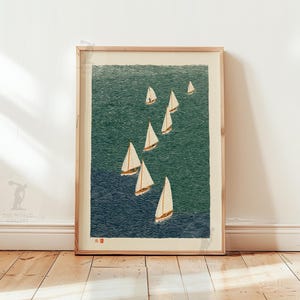 May include: A framed print featuring a fleet of sailboats on a textured ocean. The artwork uses shades of blue and green to depict the water, with white sails catching the wind. The print is in a natural wood frame, creating a nautical theme.
