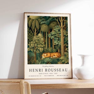 Puede incluir: Impresi&oacute;n art&iacute;stica enmarcada que representa una escena de la jungla con un tigre descansando entre un exuberante follaje verde. La obra de arte, de Henri Rousseau, incluye texto en la parte inferior. El marco es de color marr&oacute;n claro.