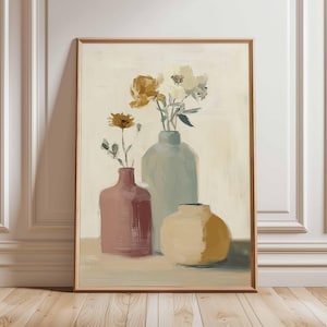 以下が含まれることがあります： 3つの花瓶と花の静物画が描かれた、額入りのアートプリント。花瓶はピンク、ブルーグリーン、イエローの色合いです。花は黄色と白で、クリーム色の背景に配置されています。