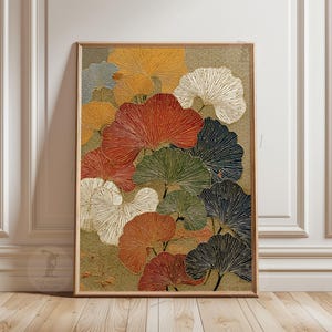 May include: A framed art print with a botanical design. The artwork depicts fan-shaped leaves in red, orange, green, white, and navy blue, set against a textured gold background. The print is displayed in a wooden frame.