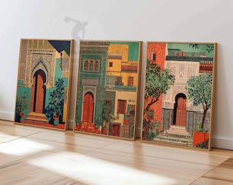 May include: Three framed art prints depicting colorful Moroccan architecture. Each print features a different building facade with arched doorways, intricate details, and vibrant hues of teal, orange, and gold. The prints are displayed on a wooden floor.