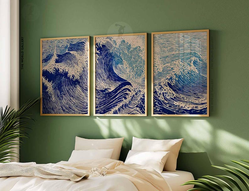 May include: Three framed art prints depicting stylized ocean waves in shades of blue and white. The artwork is displayed on a green wall above a bed with white bedding. The frames have a gold finish. The text "THE WORLD GALLERY" is visible.