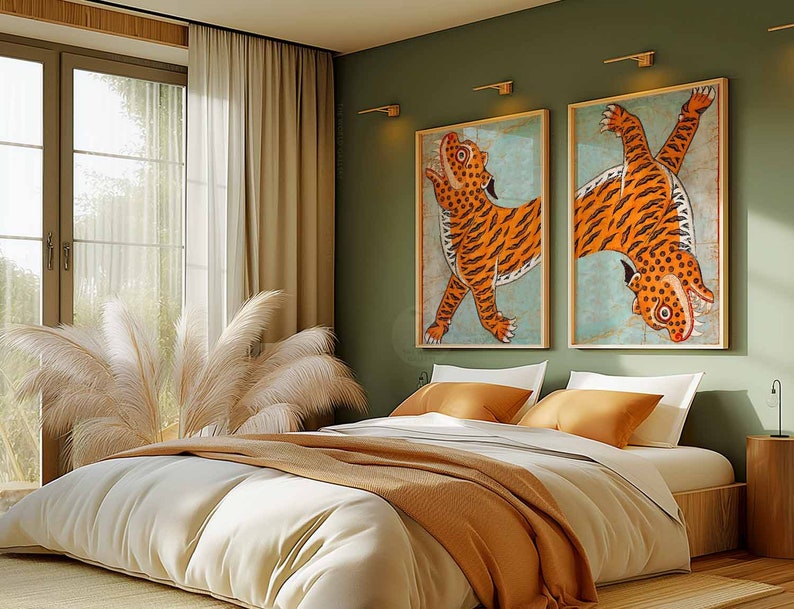 May include: A bedroom with a white bed with a brown blanket and two white pillows. There are two framed pictures of tigers on the wall behind the bed. The walls are a sage green color. There are two lamps on the wall and a small table with a lamp on it.