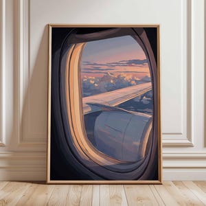 May include: A framed art print depicting a view from an airplane window. The artwork showcases a sunset with pink and orange hues, clouds, and the plane's wing and engine. The frame is a light brown color.