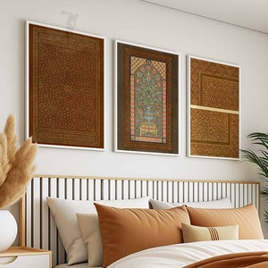 May include: Three framed prints with intricate patterns and designs in shades of brown, gold, and red. The prints are hung on a white wall above a headboard.