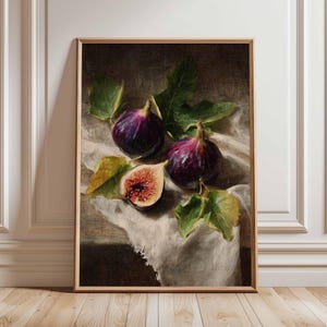 Op de afbeelding: Een ingelijst stilleven schilderij met rijpe vijgen. De dieppaarse vruchten, vergezeld van groene bladeren en een witte doek, zijn in een klassieke compositie afgebeeld. Eén vijg is doorgesneden om het rode binnenste te tonen. Het kunstwerk is in een houten lijst.