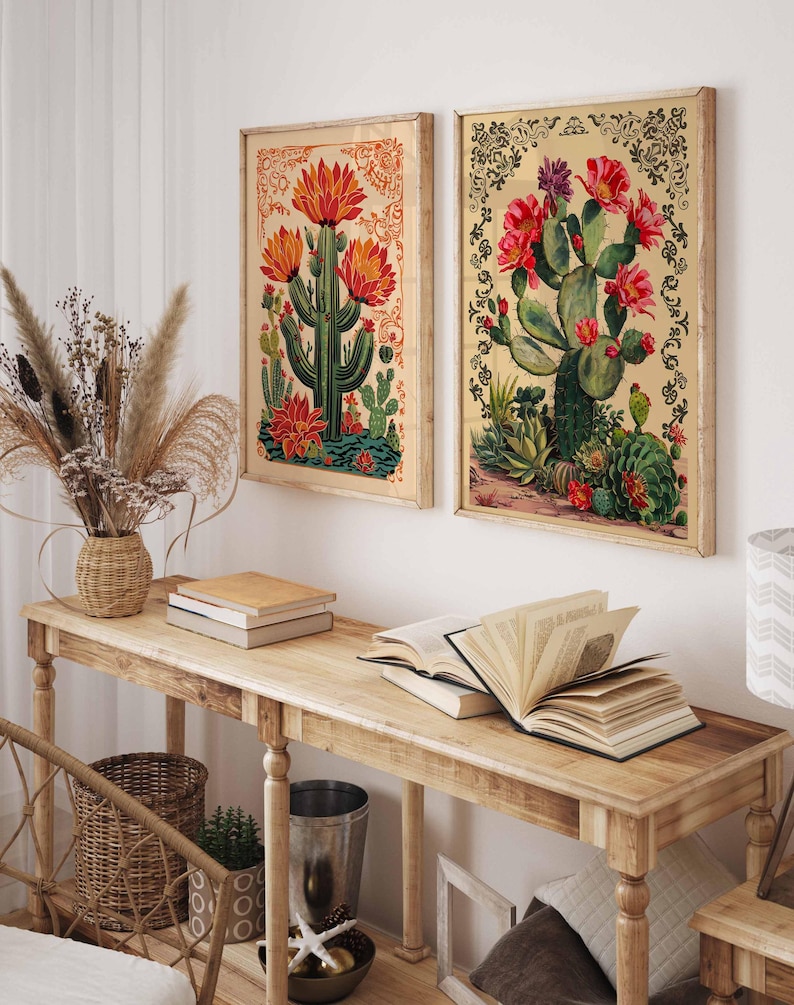 Op de afbeelding: Twee ingelijste botanische prints met illustraties van cactussen met rode bloemen. De prints hangen aan een witte muur boven een houten consoletafel.