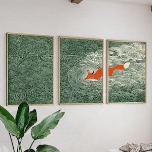 Puede incluir: Conjunto de tres láminas enmarcadas. Las láminas presentan un fondo verde con un patrón de olas. La lámina central muestra un zorro naranja nadando. Los marcos son dorados.