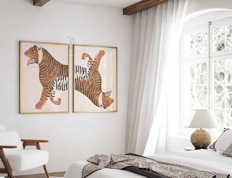 Peut inclure: Deux impressions encadr&eacute;es d'un tigre dans un d&eacute;cor de chambre minimaliste. Les impressions sont dans des cadres dor&eacute;s et pr&eacute;sentent un tigre &agrave; rayures orange et noires. Le tigre est repr&eacute;sent&eacute; dans une pose dynamique, la t&ecirc;te tourn&eacute;e sur le c&ocirc;t&eacute; et le corps &eacute;tir&eacute;. Les impressions sont accroch&eacute;es &agrave; un mur blanc, et la pi&egrave;ce est d&eacute;cor&eacute;e d'un lit blanc, d'une chaise blanche et d'une lampe blanche.