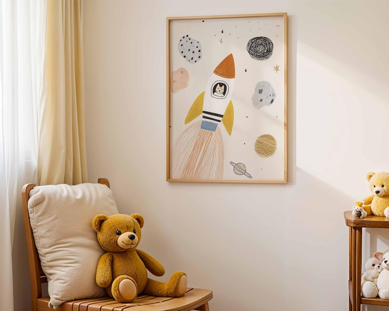 May include: A framed art print featuring a whimsical rocket ship with a cat in the cockpit, surrounded by planets and stars. The artwork is in a child's room, with a teddy bear on a wooden chair.