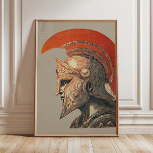 May include: A framed art print featuring a profile illustration of a Spartan warrior wearing a detailed helmet with a prominent orange crest. The artwork uses a colour palette of orange, black, and cream, with intricate line work and shading.
