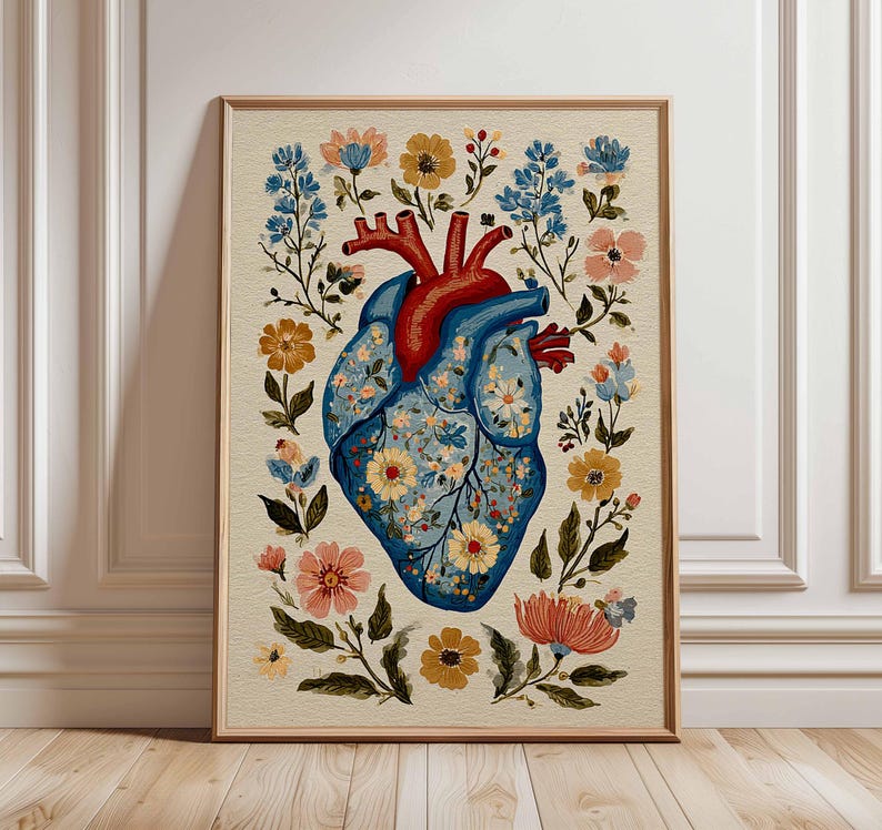 May include: A framed art print featuring a stylized anatomical heart. The heart is blue with floral patterns, surrounded by colorful flowers and foliage. The top of the heart is red. The artwork is set against a cream-colored background.