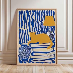 May include: A framed art print with a stylized illustration. A yellow cat rests on a stack of blue books. A yellow lamp and blue vase are also depicted. The background has a blue and cream wavy pattern. The artwork is in a wooden frame.
