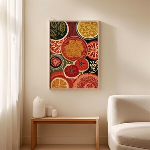 May include: A framed art print featuring a colorful, abstract design of various food items. The artwork includes images of pasta, tomatoes, oranges, and other elements in shades of red, orange, yellow, and green. The print is displayed on a light-colored wall.