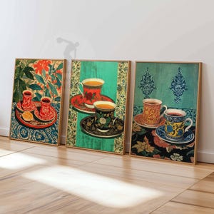 Peut inclure: Trois impressions d'art encadrées représentant des illustrations stylisées de tasses et de soucoupes. Les impressions ont une esthétique vintage, avec des fonds floraux et à motifs dans des tons de rouge, vert et bleu. Les tasses sont remplies d'un liquide doré.