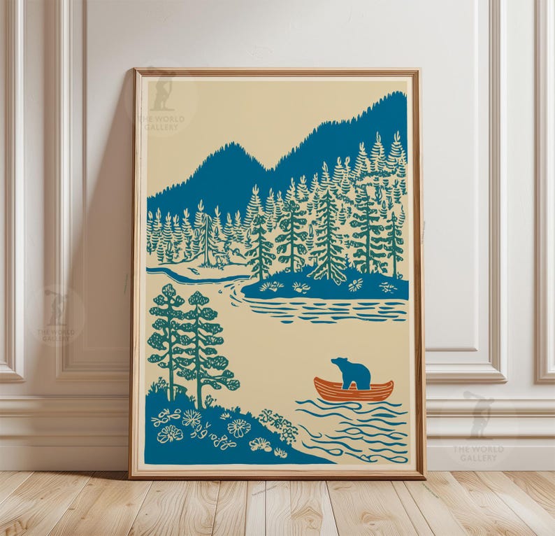 May include: A framed art print featuring a serene landscape with teal mountains, trees, and a river. An orange canoe with a bear floats on the water. The artwork has a vintage, minimalist style with a cream-colored background.