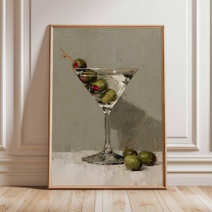 May include: A framed painting of a martini glass filled with olives. The artwork features a clear glass with a stem, filled with a clear liquid and green olives. The background is a muted gray, and the painting is in a wooden frame.