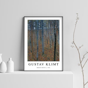 May include: A black framed poster featuring a painting by Gustav Klimt titled "Beech Grove I, 1902". The painting depicts a forest scene with tall, slender trees in shades of blue and green, with a ground covered in fallen leaves in shades of brown and yellow.