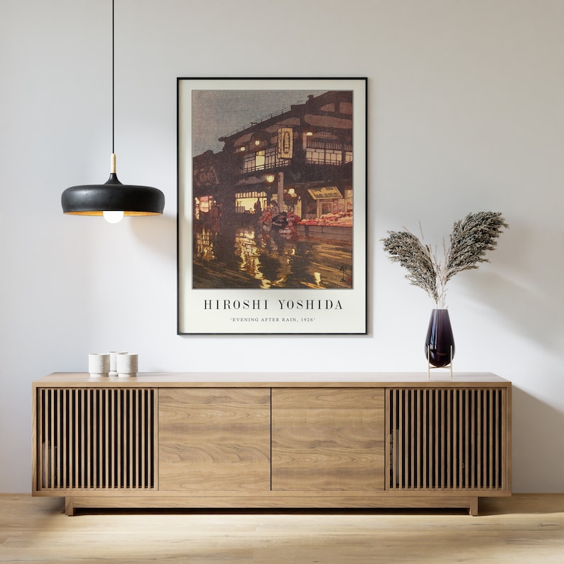 May include: A framed print of a Japanese street scene at night, with a building lit up and reflections in the wet street. The print is titled "Hiroshi Yoshida" and "Evening After Rain, 1925".