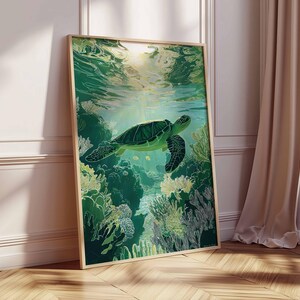 May include: A framed art print featuring a green sea turtle swimming underwater. The artwork depicts the turtle above a coral reef, with sunlight filtering through the water. The frame is a light wood color, and the overall theme is marine life.