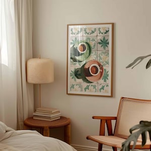 May include: A framed art print featuring two coffee cups, one green and one pink, on a tile background. The cups are filled with coffee and have a top-down perspective. The artwork is in a room with a lamp, side table, and chair.