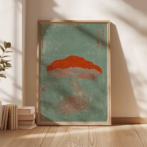 May include: A framed print featuring a stylized orange mushroom illustration against a teal background. The artwork has Japanese text and a woodblock print aesthetic. The print is displayed in a light-colored wooden frame.