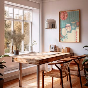 May include: A light-filled room with a wooden desk and two chairs. A framed Japanese print depicting drums hangs on the wall. A large window offers a view of trees. A silver pendant light hangs above the desk.