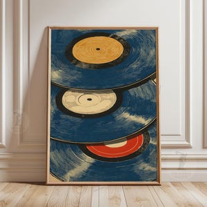 May include: A framed art print featuring three vintage vinyl records. The records have a blue background with yellow, white, and red center labels. The artwork is in a vertical orientation and has a wooden frame.
