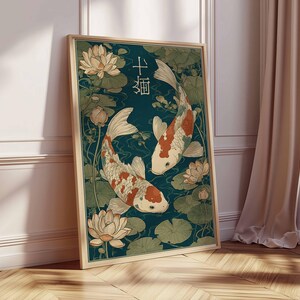 May include: Framed art print featuring two koi fish swimming among water lilies. The fish have white bodies with orange and red markings. The background is a deep teal color, and the artwork is in a wooden frame.