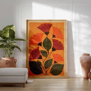 May include: A framed floral art print featuring stylized red and orange flowers with green leaves against an orange background. The artwork is displayed on a wooden floor, next to a potted plant and a gray ottoman. Decorative vases are also present.