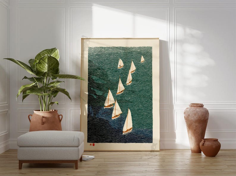 May include: A framed print of sailboats on a teal ocean. The artwork features several white sailboats with tan sails against a textured background. The print is displayed in a room with a plant, ottoman, and decorative vases.
