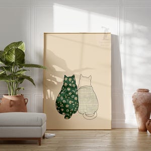 Puede incluir: Un gran cuadro enmarcado con dos figuras de gatos estilizados. Un gato est&aacute; adornado con un estampado floral verde, el otro con un dise&ntilde;o de cuadros. La obra de arte est&aacute; sobre un fondo beige, con una est&eacute;tica minimalista. La impresi&oacute;n se muestra en una habitaci&oacute;n.