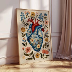 May include: A framed art print featuring a stylized anatomical heart design. The heart is depicted in shades of blue and red, adorned with floral patterns and surrounded by colorful flowers and foliage. The artwork is set against a neutral background.