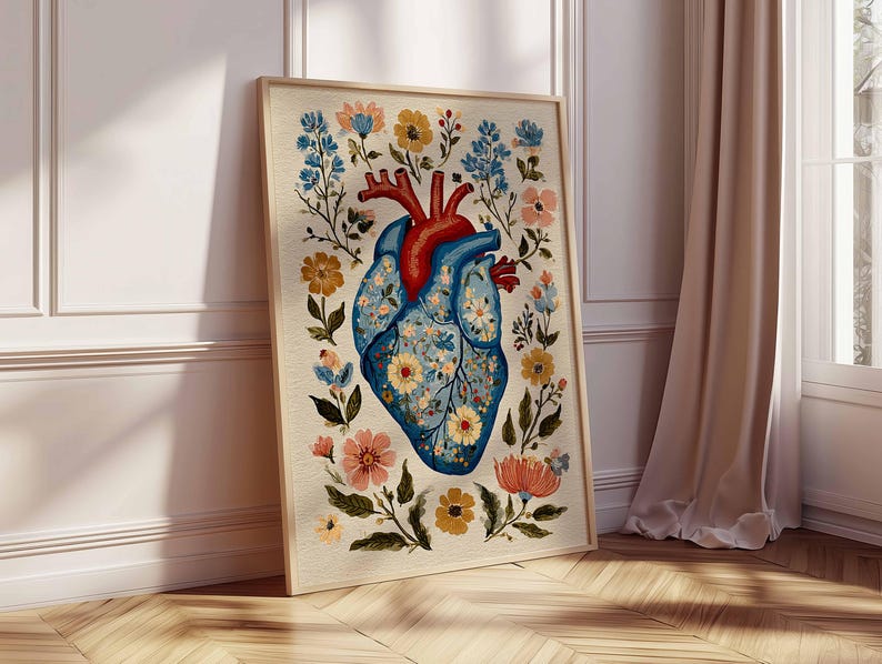 May include: A framed art print featuring a stylized anatomical heart design. The heart is depicted in shades of blue and red, adorned with floral patterns and surrounded by colorful flowers and foliage. The artwork is set against a neutral background.