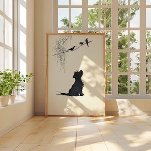 K&ouml;nnte beinhalten: Ein gerahmter Kunstdruck mit einer schwarzen Silhouette eines Hundes, der zu V&ouml;geln auf einem Ast aufblickt. Das Kunstwerk hat einen cremefarbenen Hintergrund und einen Holzrahmen. Die Szene wird von nat&uuml;rlichem Licht von einem nahegelegenen Fenster beleuchtet.