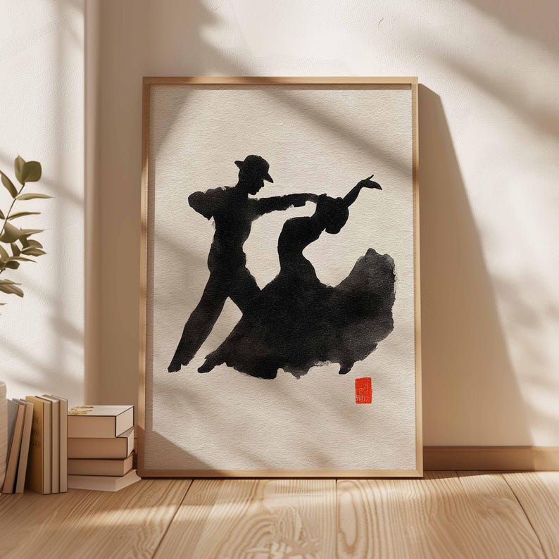 K&ouml;nnte beinhalten: Gerahmter Kunstdruck mit einer schwarzen Tintensilhouette eines tanzenden Paares. Der Mann tr&auml;gt einen Hut, das Kleid der Frau ist ausgestellt. Das Kunstwerk hat einen minimalistischen Stil mit einem roten quadratischen Stempel. Der Rahmen ist helles Holz.