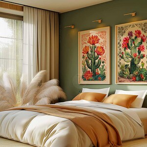 Op de afbeelding: Twee ingelijste botanische prints van cactussen met roze bloemen, hangend aan een groene muur boven een wit bed met oranje en bruine beddengoed.