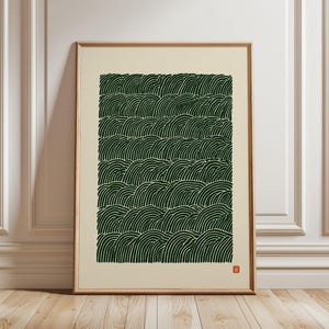 May include: A rectangular framed wall art print featuring a repeating pattern of dark green, curved, wave-like lines on a cream-coloured background. A small, square, orange-red stamp is visible in the bottom right corner of the print.