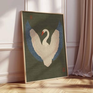 Pode incluir: Impress&atilde;o art&iacute;stica emoldurada com um cisne com as asas abertas. O cisne tem penas brancas com pontas das asas azuis e um bico vermelho, contra um fundo verde escuro. A obra de arte est&aacute; numa moldura de madeira e encostada a uma parede branca.