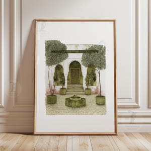 May include: Art print in a wooden frame showing a courtyard with a fountain, trees, and an arched doorway. The artwork uses a muted palette of greens, browns, and beige. The print is displayed on a white wall.
