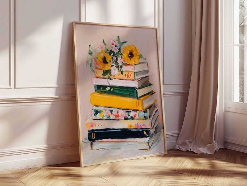 May include: A framed art print featuring a stack of books with a floral arrangement on top. The books are painted in various colors, including yellow, green, and floral patterns. The sunflowers and other flowers add a touch of nature to the artwork. The frame is a light wood color.
